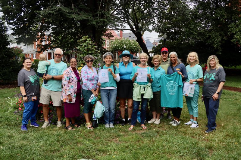 Volunteers who helped hang teal ribbons around Lewes Aug. 20 are (l-r) Kim O’Neill, Beebe Oncology; Greg Merk holding Van Daube; Rep. Alonna Berry, D-Milton; Marsha Sterling; Wan Chen; Jan Gilmour; Janet Liggett; Lynda Gluch; Bob Gilmore; Rita Williams, Beebe Healthcare; Sally Oberle, Delaware Ovarian Cancer Foundation vice president of special projects; and Regina Newell, Beebe Oncology.